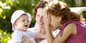 Mother and daughter (8-9) playing with baby boy (6-9 months), peekaboo