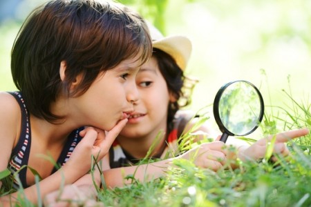 Happy kid exploring nature with magnifying glass