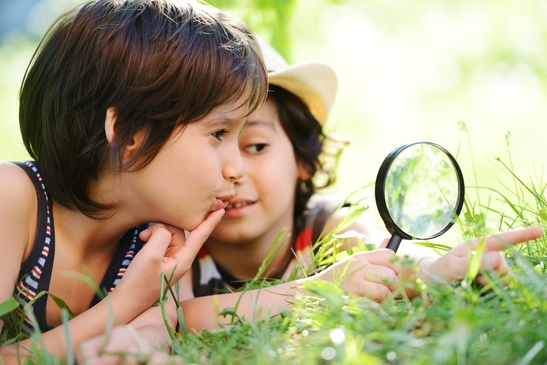 Happy kid exploring nature with magnifying glass
